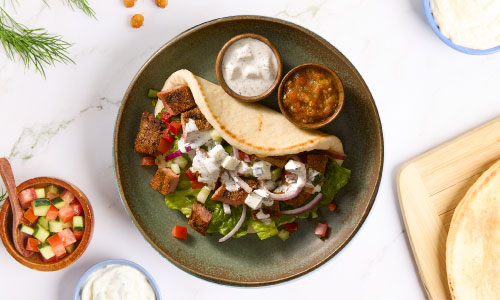 fresh gyro on a plate with sauces on the side