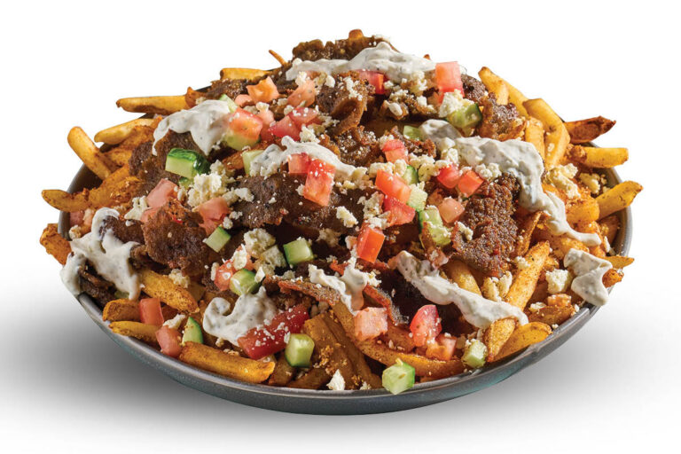 Loaded fries topped with gyro meat, feta, tomato, cucumber, and creamy sauce on a white background.